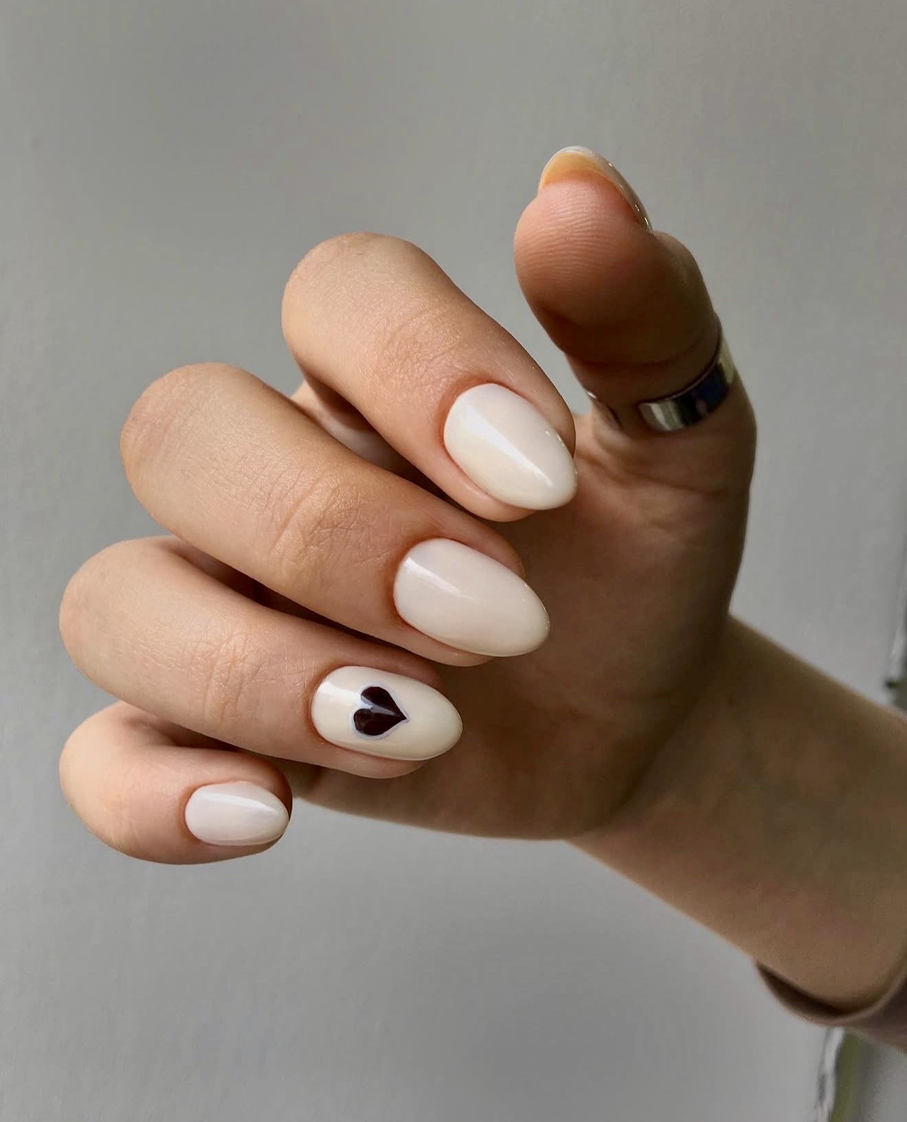 Creamy Nude Almond Nails with Black Heart Accent